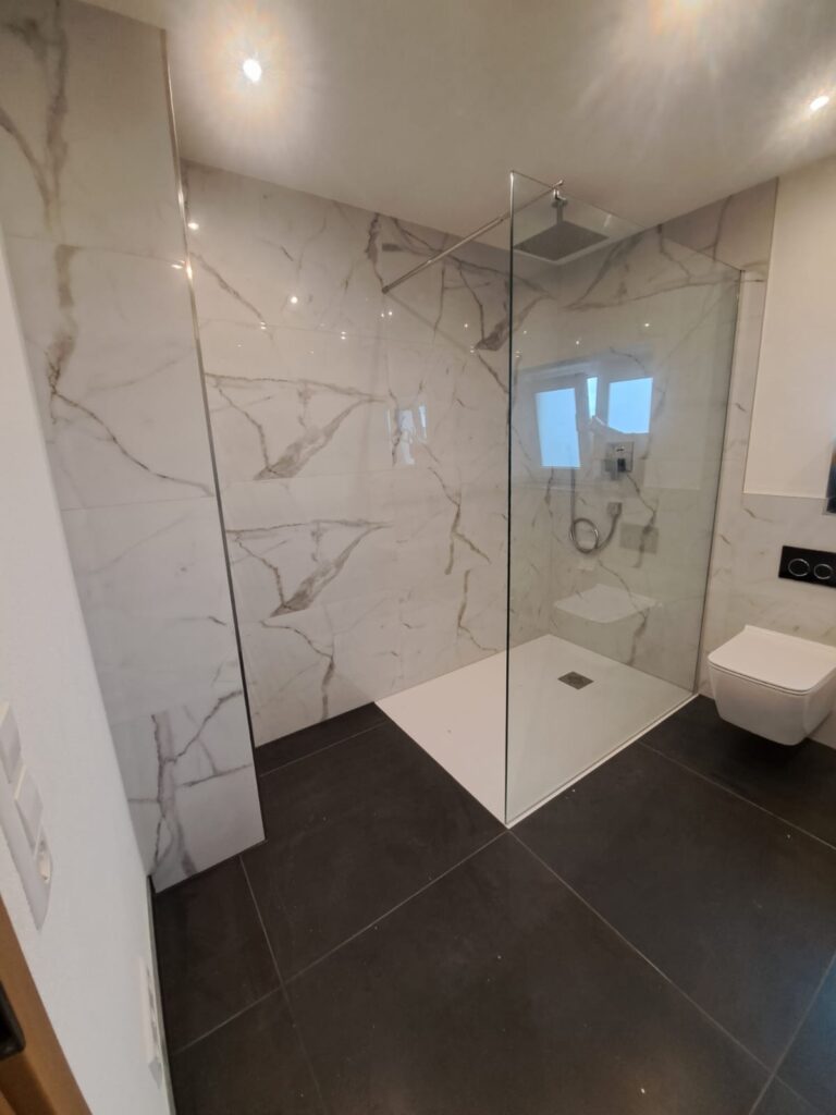 Badezimmer mit großformatigen Fliesen in Marmoroptik und bodengleicher Dusche